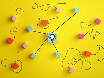 lightbulb against yellow background, with colourful squares and lines